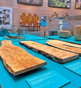 Sinisellä tasolla on kolme leveää visalankkua. Taustalla on kolmenistuttava visapuinen sohva.